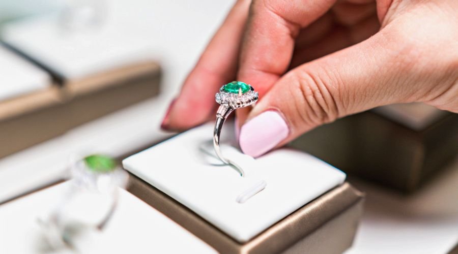 hand picking up wedding emerald ring in a box