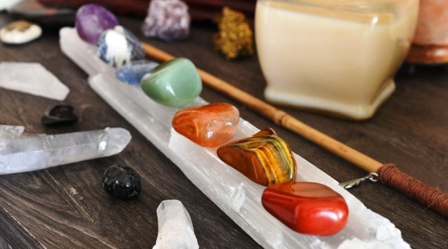A close up image of seven chakra healing crystals charging on a selenite wand