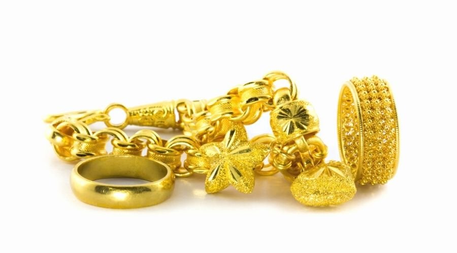Various pieces of gold jewelry in a pile isolated against a white background