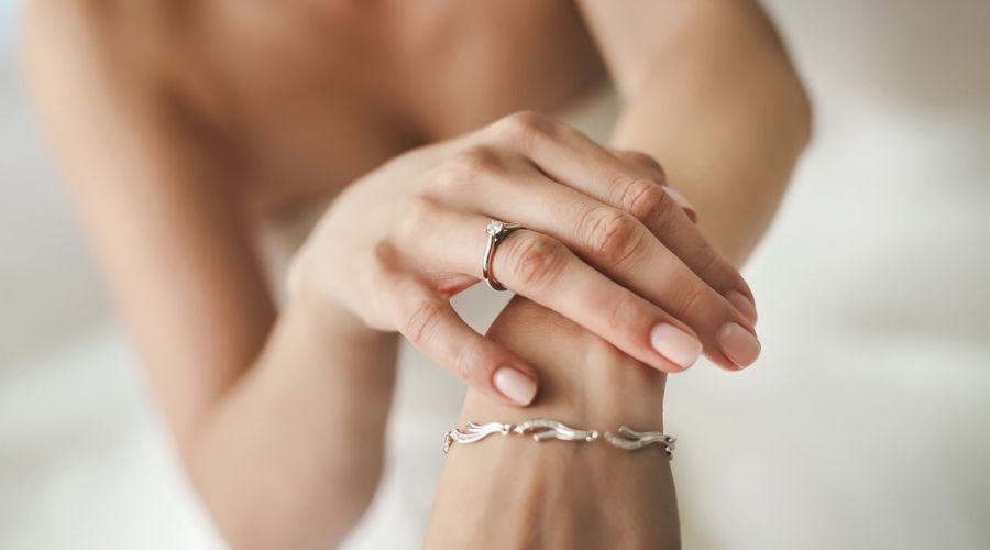 close up of the hands of a bride wearing a silver ring and a bracelet